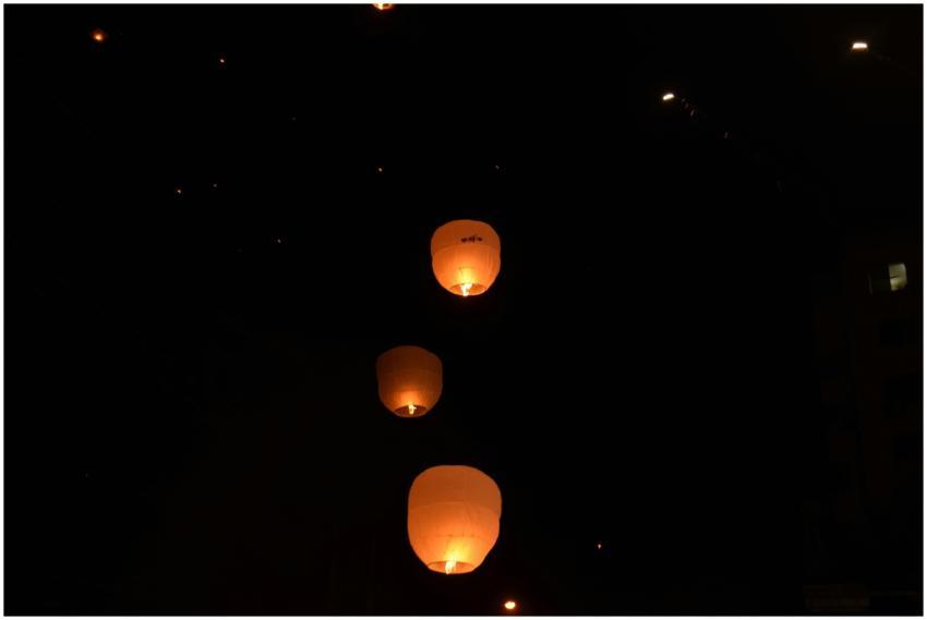 Sky lanterns glowing warmly as they ascend into th