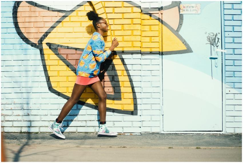 A young woman in vibrant attire running past a col