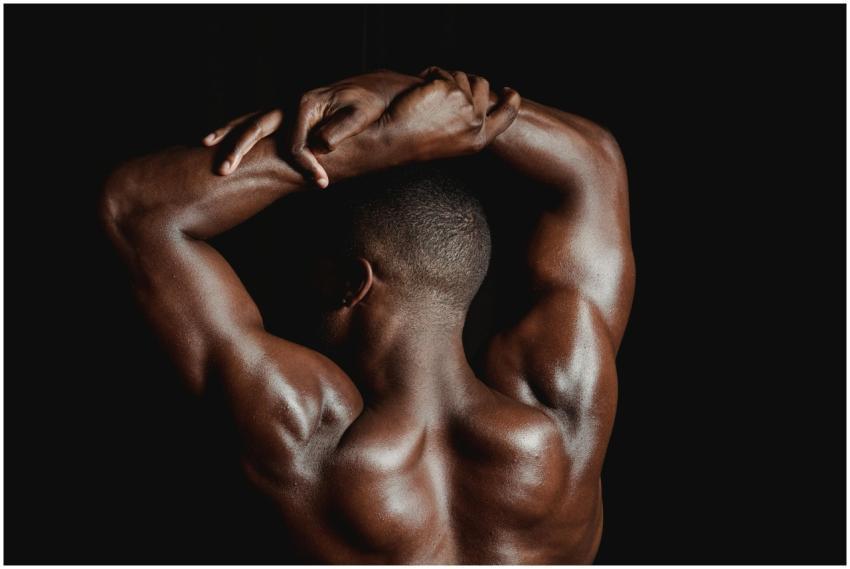 A strong, shirtless black man posing from behind,