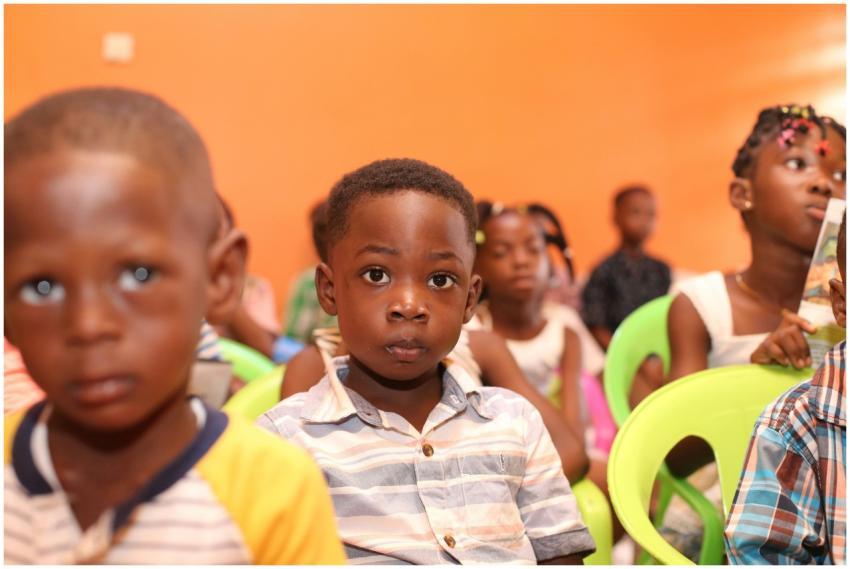 A group of children seated in a colorful classroom