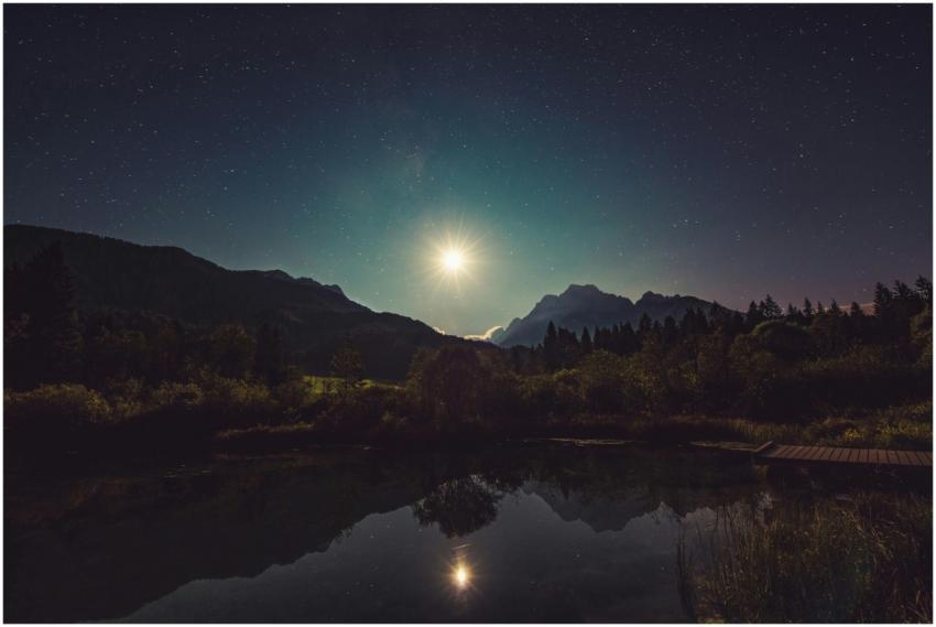 A peaceful view of moonlit mountains reflected in