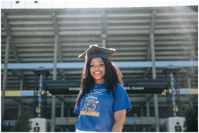 Smiling woman in graduation attire celebrating out