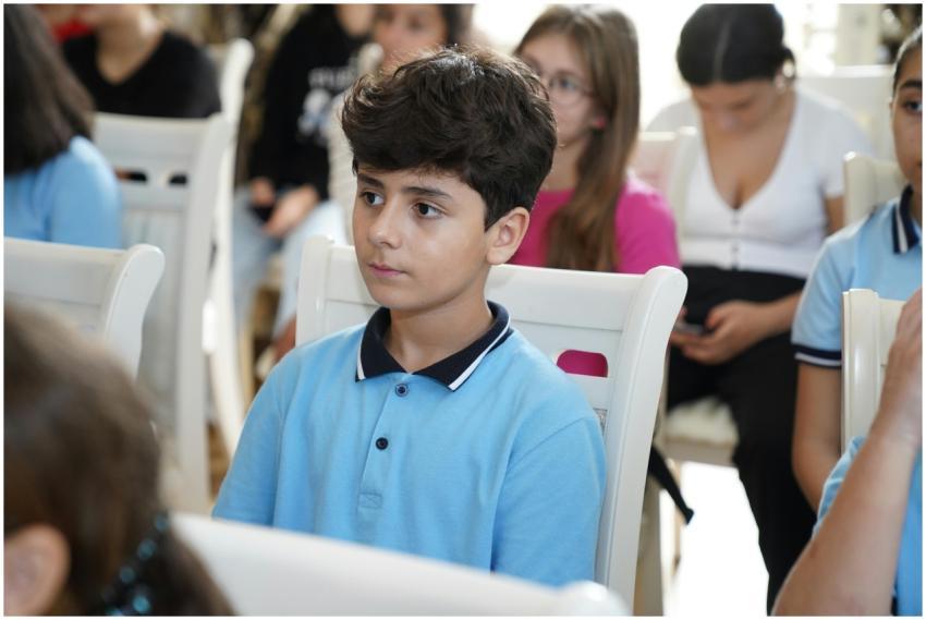 A student in a blue shirt attentively listens duri