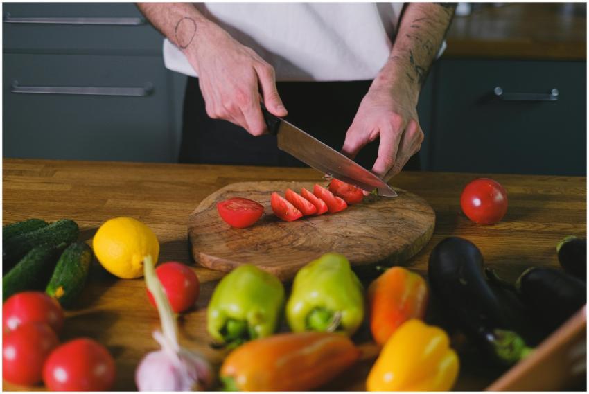 A person slicing tomatoes on a wooden chopping boa