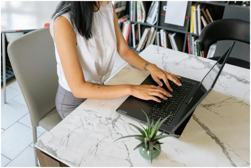 A professional woman typing on a laptop in an offi