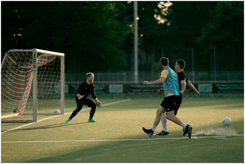 Two soccer players and a goalie in action during a