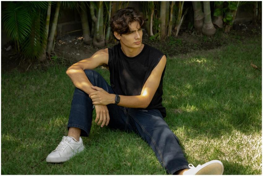 A young man in jeans and a sleeveless shirt sits t