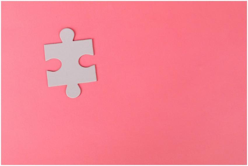 A single puzzle piece set against a vibrant pink b