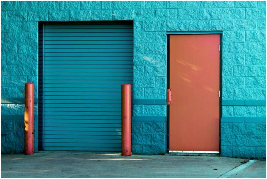 Vivid blue wall with a closed door and shutter in