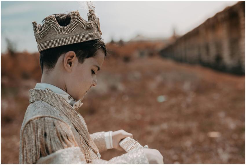 A child dressed as a prince wearing a crown in an