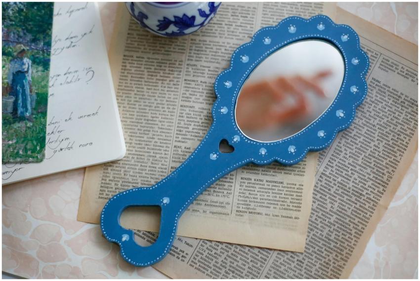 A vintage-style blue hand mirror placed on old new