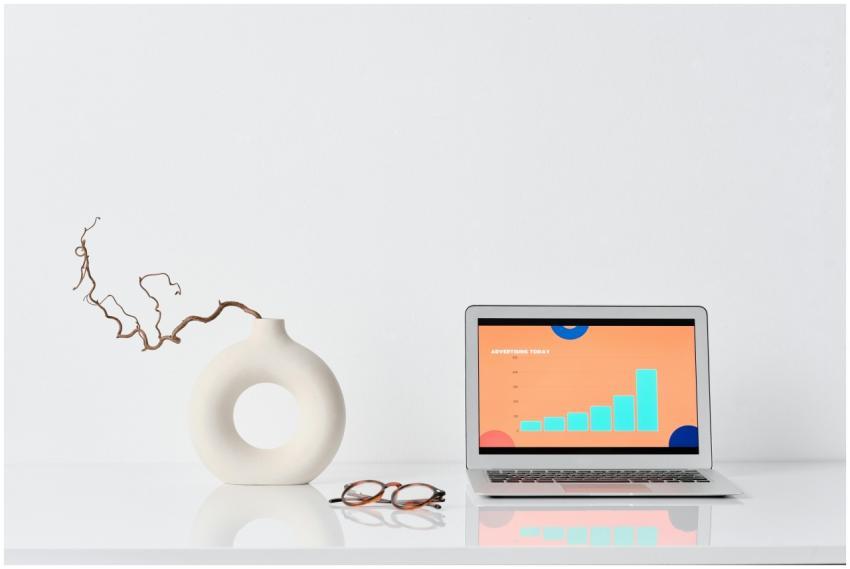 A minimalist workspace with a laptop, ceramic vase