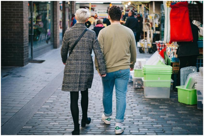 A couple holds hands walking through a bustling ur