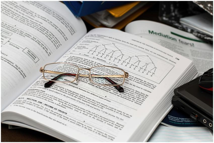 An open book with reading glasses, surrounded by s