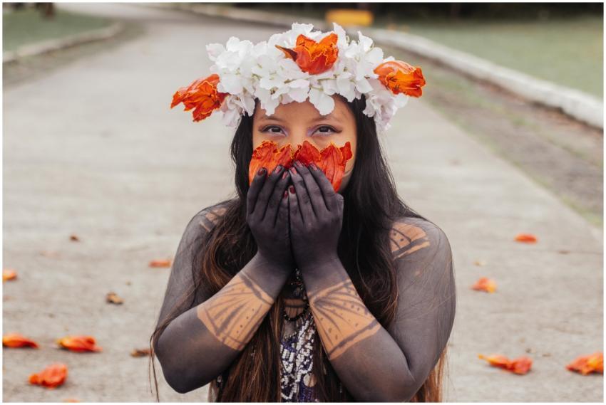 A woman adorned with a flower wreath and tribal ta