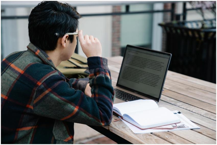 A student studies with a laptop and notebook outdo