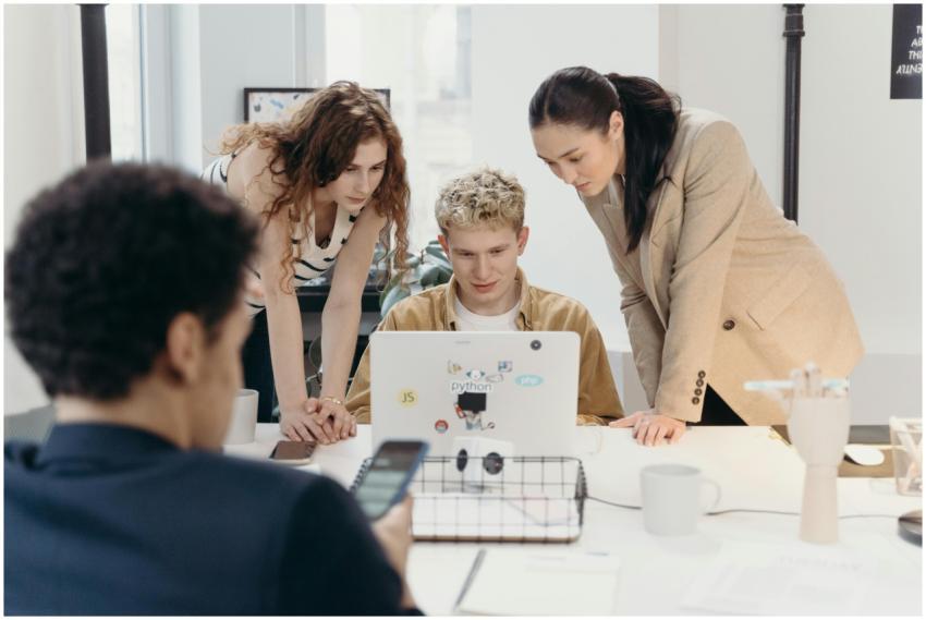 Three colleagues collaborate on a laptop, embodyin
