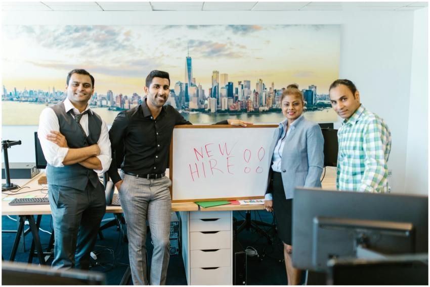 Diverse team standing with 'New Hire' sign, symbol