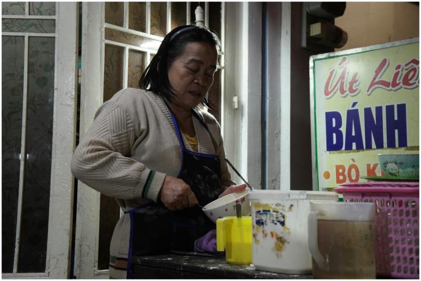 A woman preparing Vietnamese banh dish at a stree