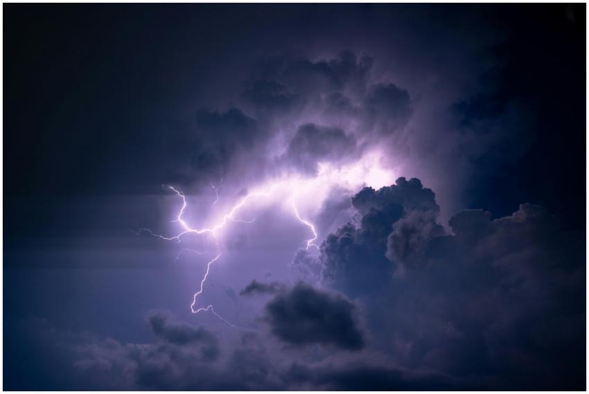 A powerful lightning bolt illuminates dark storm c