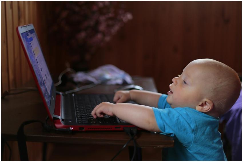 Cute baby boy engaged with a laptop indoors, showi