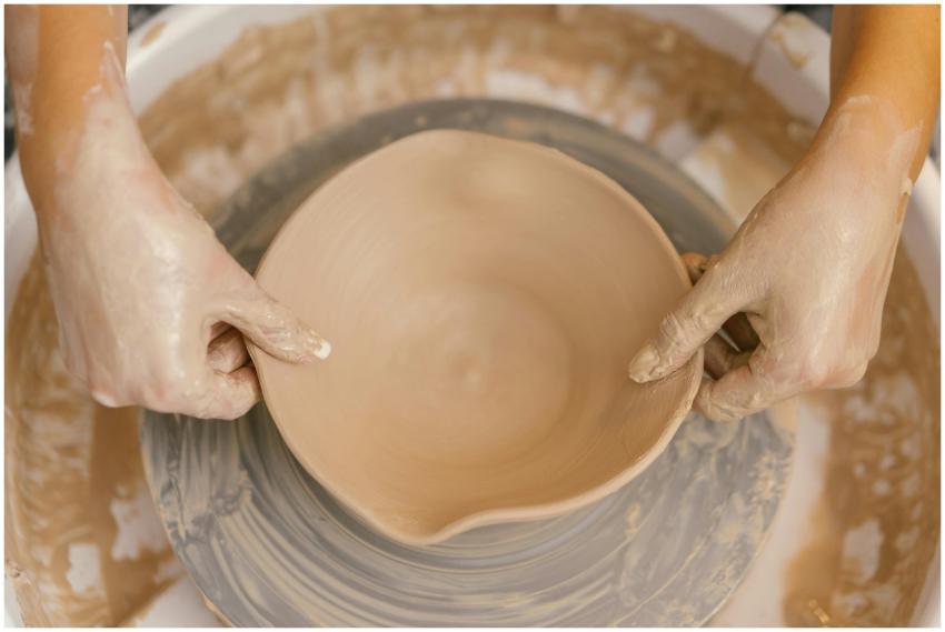 Close-up of hands shaping a ceramic bowl on a pott