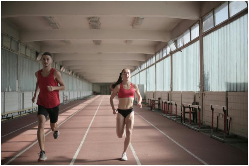 Male and female athletes running on an indoor trac