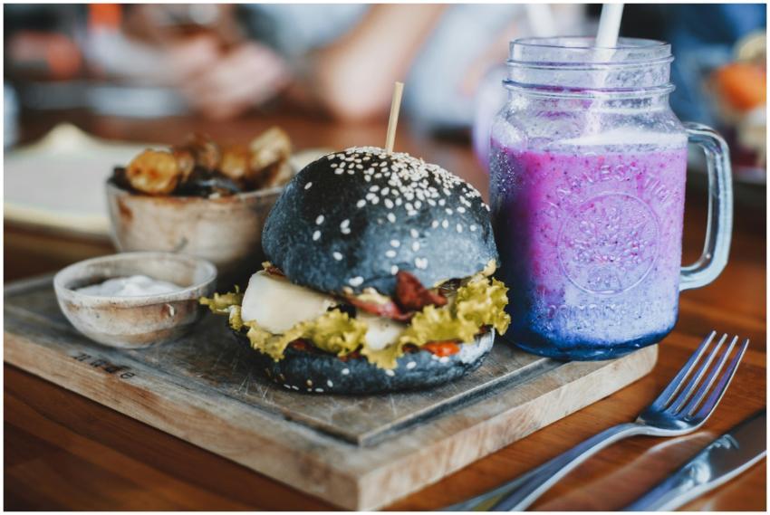 A gourmet black bun burger served with a vibrant b