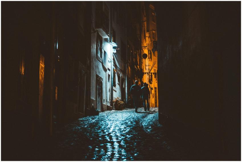 Silhouettes of people walking at night in a narrow