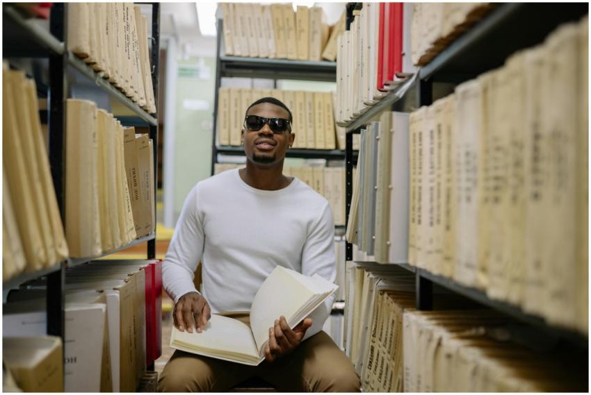 African American man with sunglasses reads a Brail