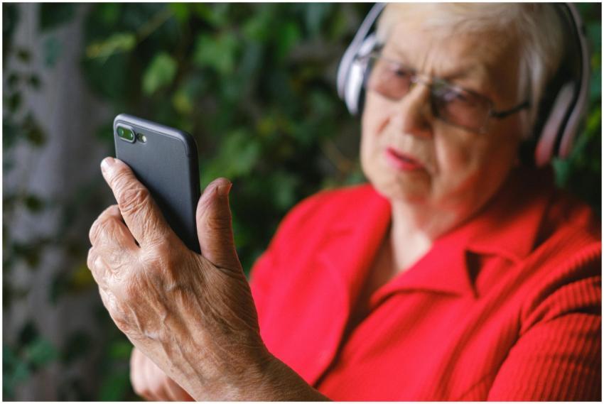 Senior woman in red using smartphone with headphon