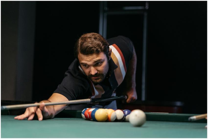Focused man playing billiards, aiming a shot on a