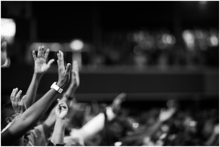Black and white image of audience with hands raise