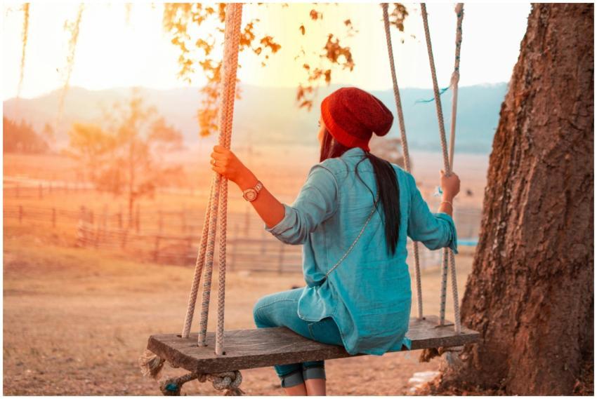 Woman in a beanie on a swing, relishing the sunset