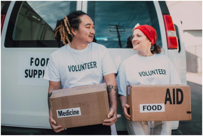 Two smiling volunteers carrying boxes labeled food