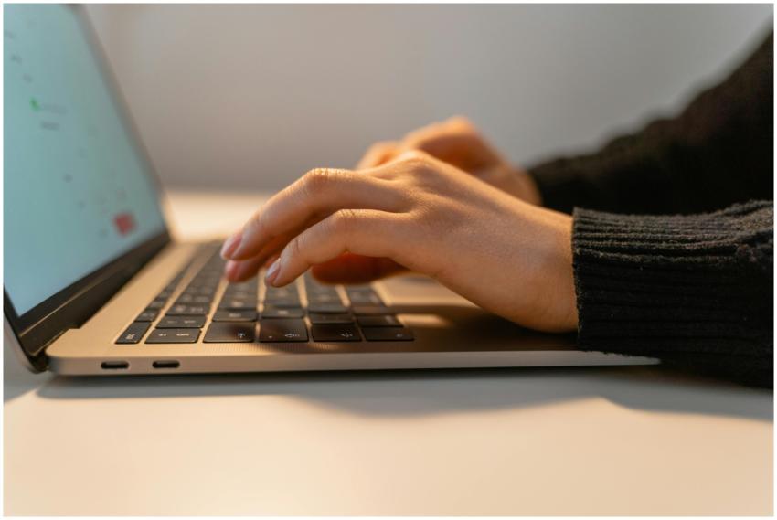Close-up view of hands typing on a laptop keyboard