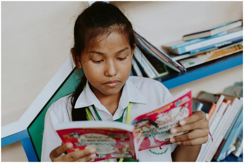 A young girl in a school uniform deeply engaged in