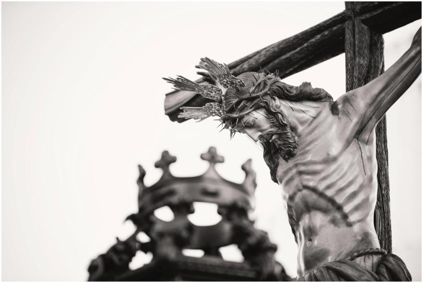A dramatic close-up of a crucifix statue outdoors