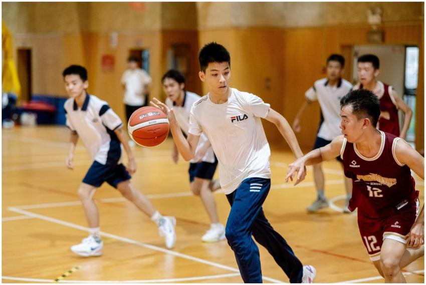 Teen boys playing competitive basketball indoors,