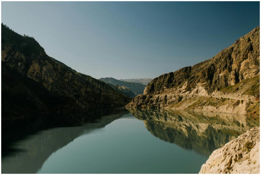 Serene mountain lake reflecting rocky cliffs under