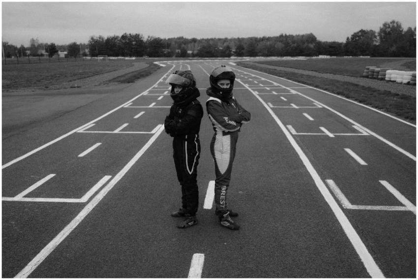 Two karting racers standing back-to-back on a race