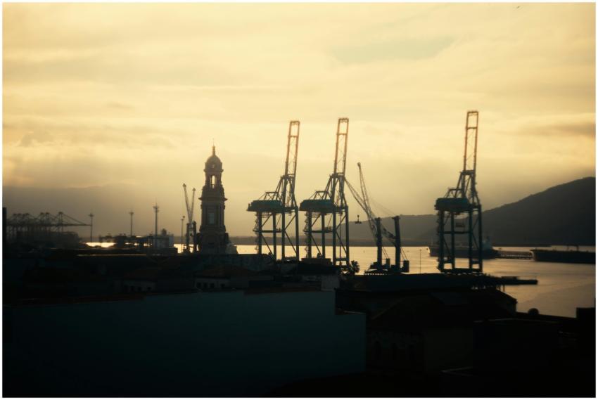 Silhouette of cranes and clock tower at sunset alo