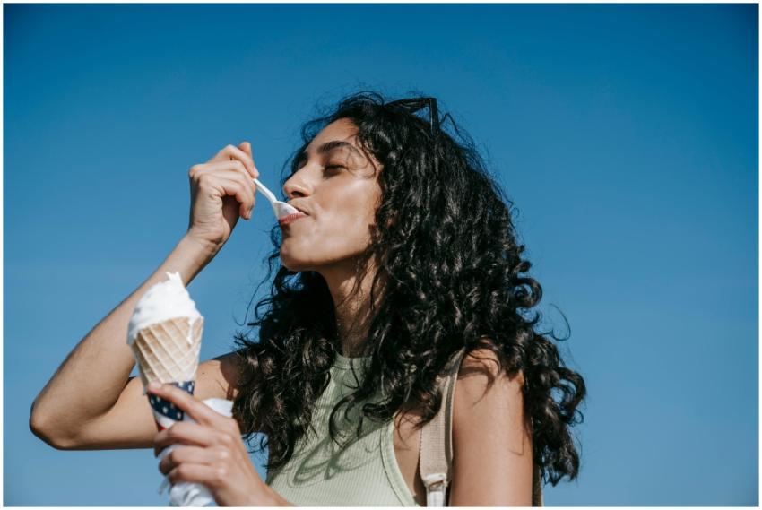 Woman savors creamy ice cream cone outdoors on a s