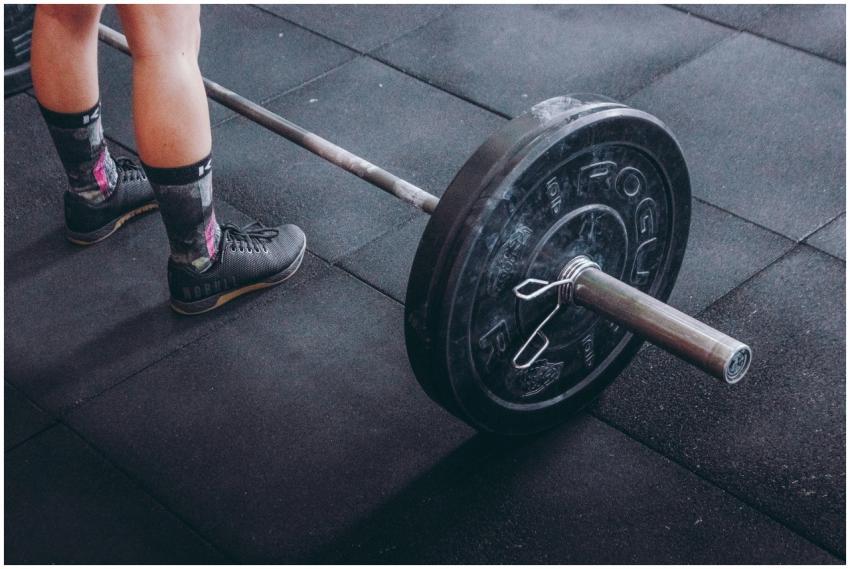 Close-up of an athlete's legs beside a barbell, re