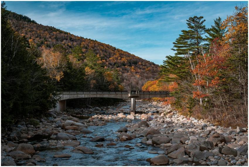 A picturesque bridge crosses a rocky stream amidst