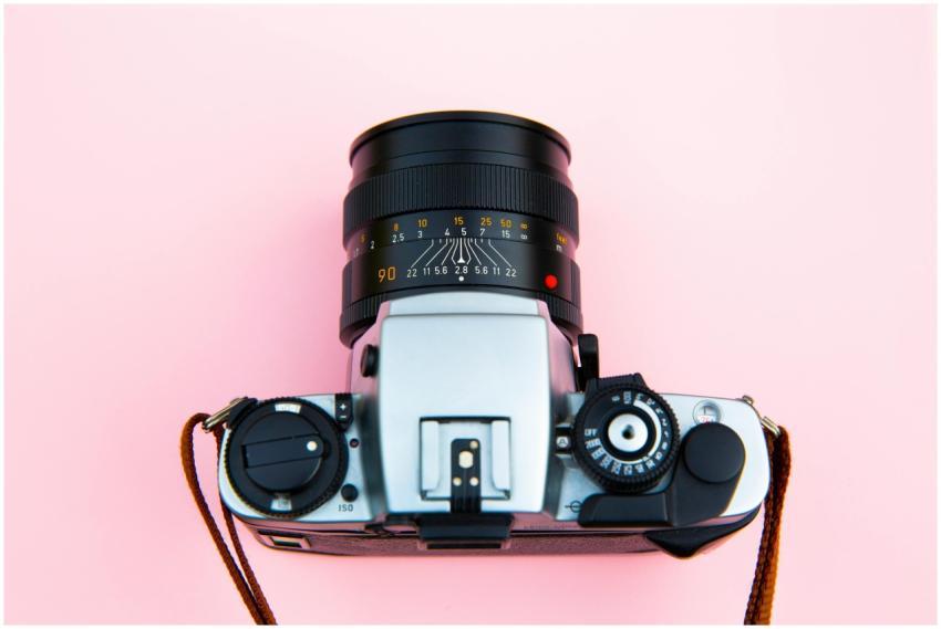 A classic analog camera with a lens on a vibrant p