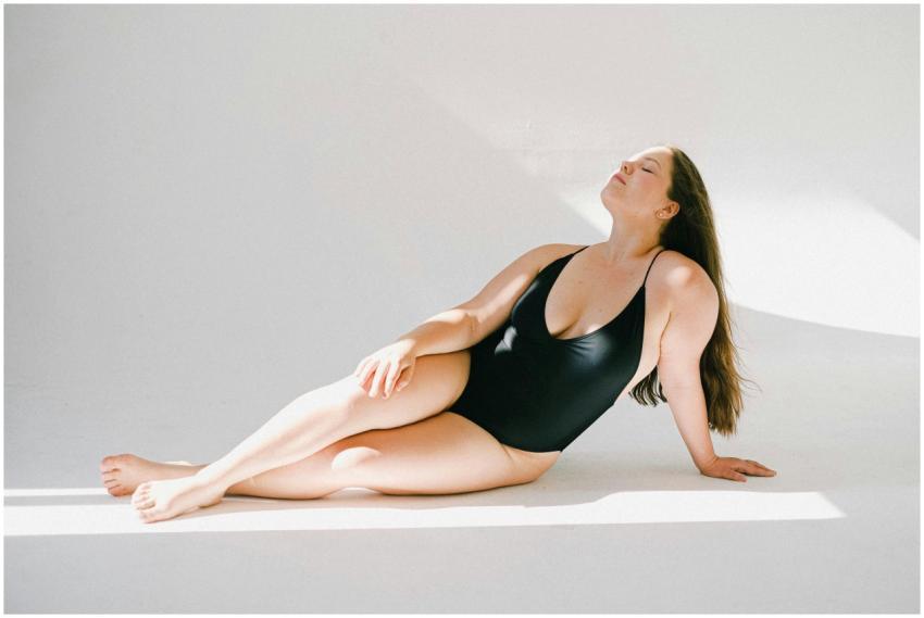 A confident plus-size woman in a black swimsuit po
