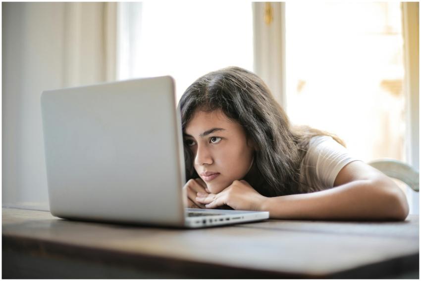 A young woman relaxes indoors using her laptop at