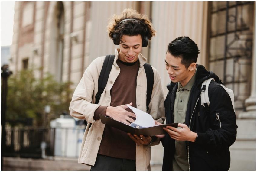 Smiling multiracial classmates turning pages of fi