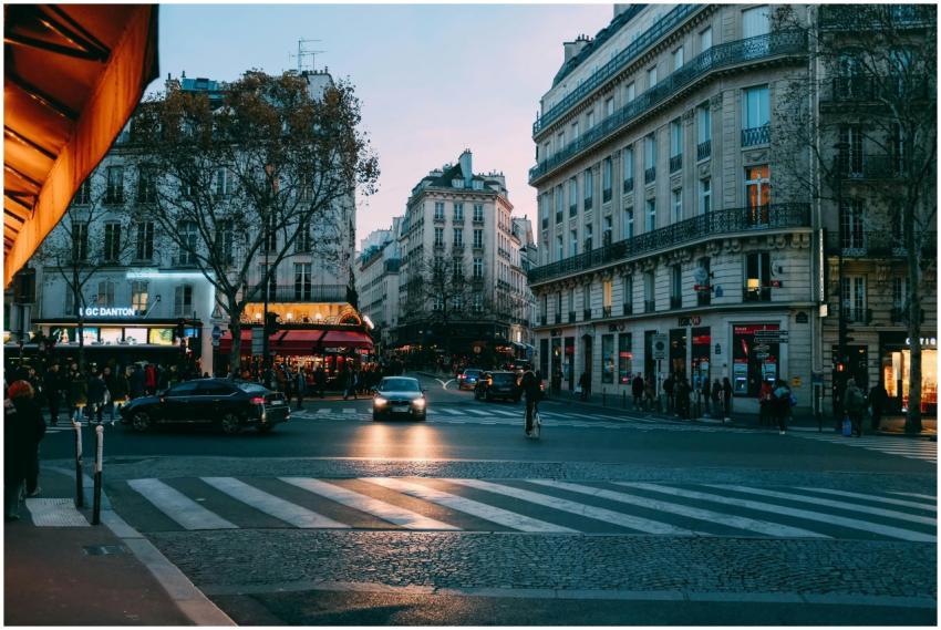 Urban street scene at dusk with cars and pedestria